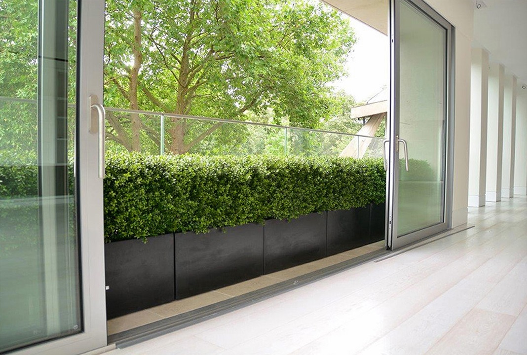 artificial hedge in black trough glass balustrade